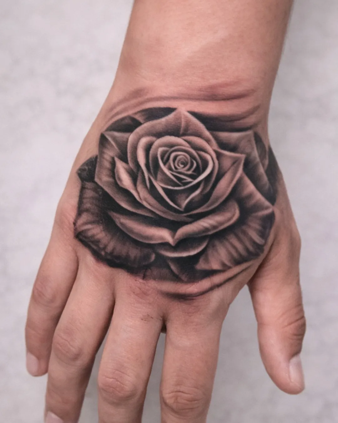 Rose en noir et gris réaliste sur le dos de la main